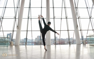La ballerina Helen Li in una pausa pomeridiana nella hall del Kansas City Kauffman Center for the Performing Arts; rilassata, esegue una páng tuǐ tǎng shēn (旁腿躺身), o 