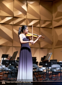 Già in abito lungo per lo spettacolo, la violinista Fiona Zheng approfitta dell'ultima opportunità per esercitarsi sul palco