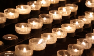 File di candele votive illuminano la cattedrale (foto di Tiffany Yu). 